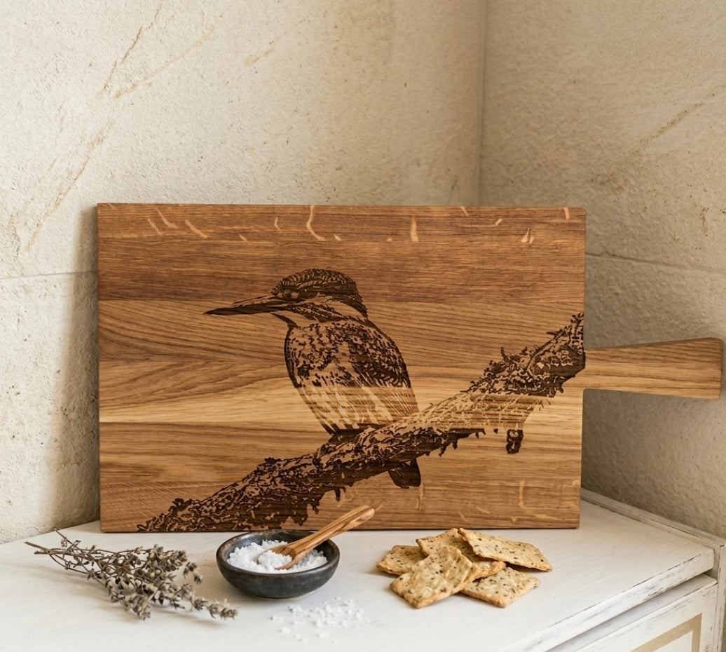 ​Hochwertiges Holzbrett aus Eiche mit kunstvoller Lasergravur eines Eisvogels auf einem Ast, markante Maserung, perfekt als dekoratives Servierbrett oder Geschenk.