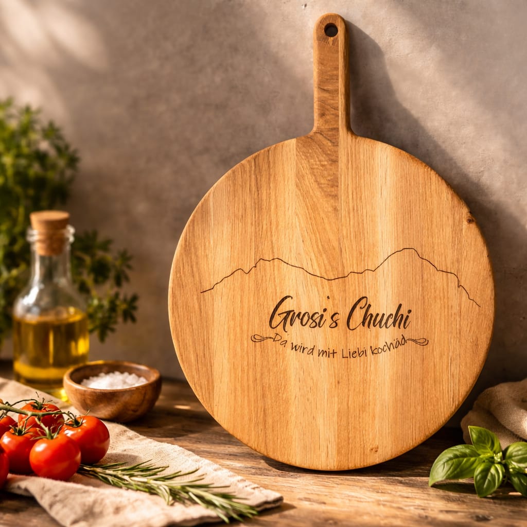 Rundes Holzschneidebrett aus Eichenholz mit Gravur ‚Grosi's Chuchi‘ und einem Bergmotiv.